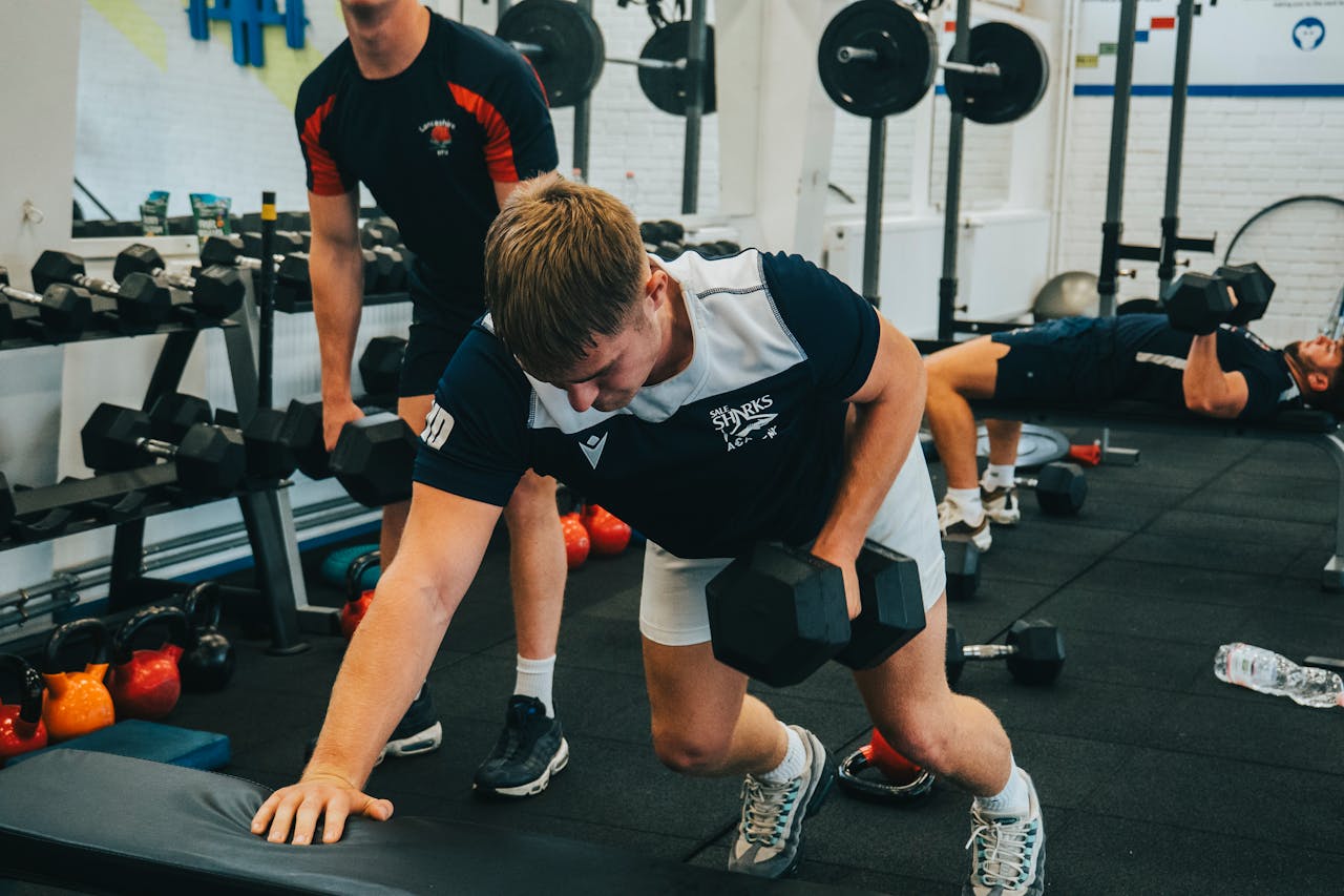 Men lifting dumbbells during a workout session in a gym. Strength and fitness training.